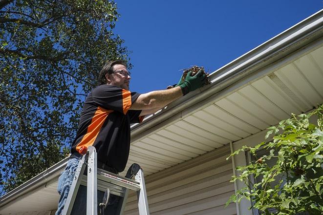 maintenance worker using a ladder to repair a gutter in Ada, OH